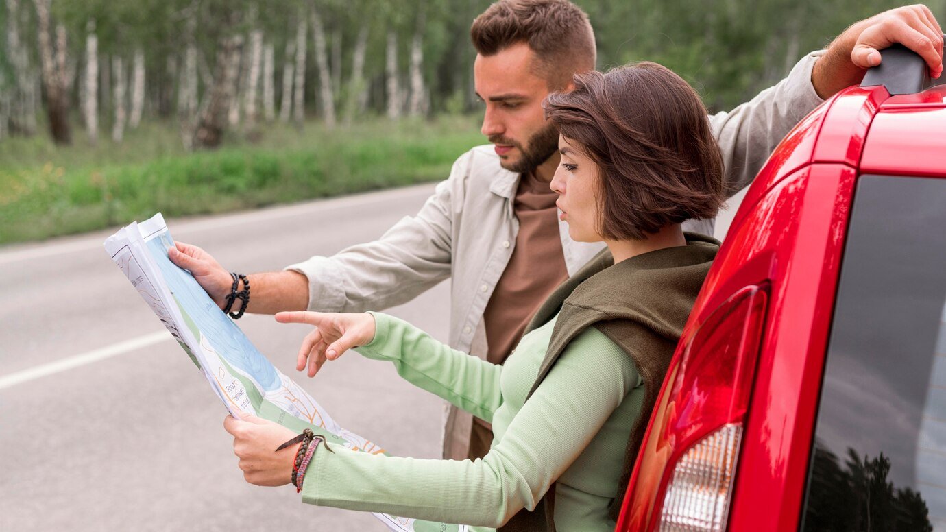 young couple standing near car looking map_23 2148693725